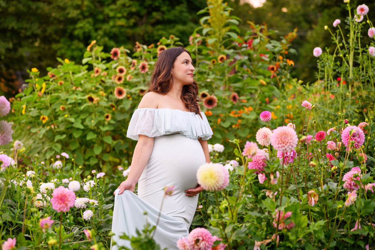 brown-haired pregnant momm-to-be wearing a mint maternity dress standing in a flower field for her Burlington outdoor maternity photos 