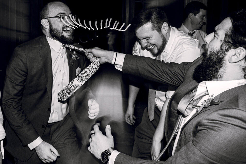 A black and white photo  of men dancing at a wedding.