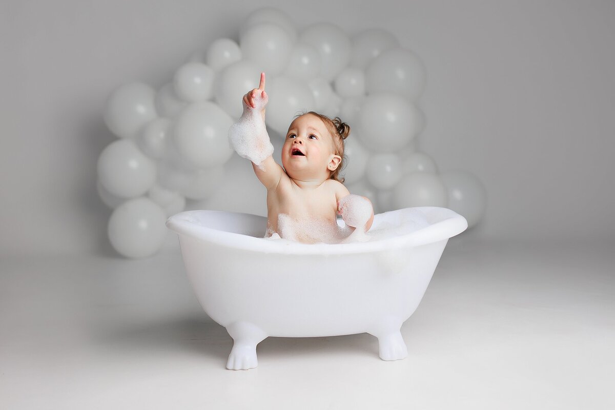  Baby in metal tub surrounded by bubbles at Austin milestone photo studio