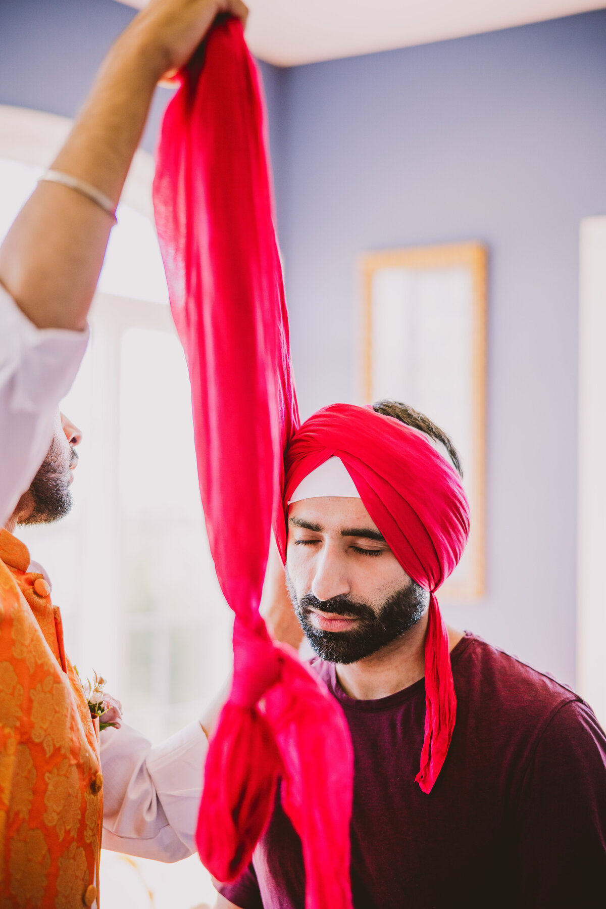 A sikh groom gets ready for the wedding by getting his turban pagh tied by a family member