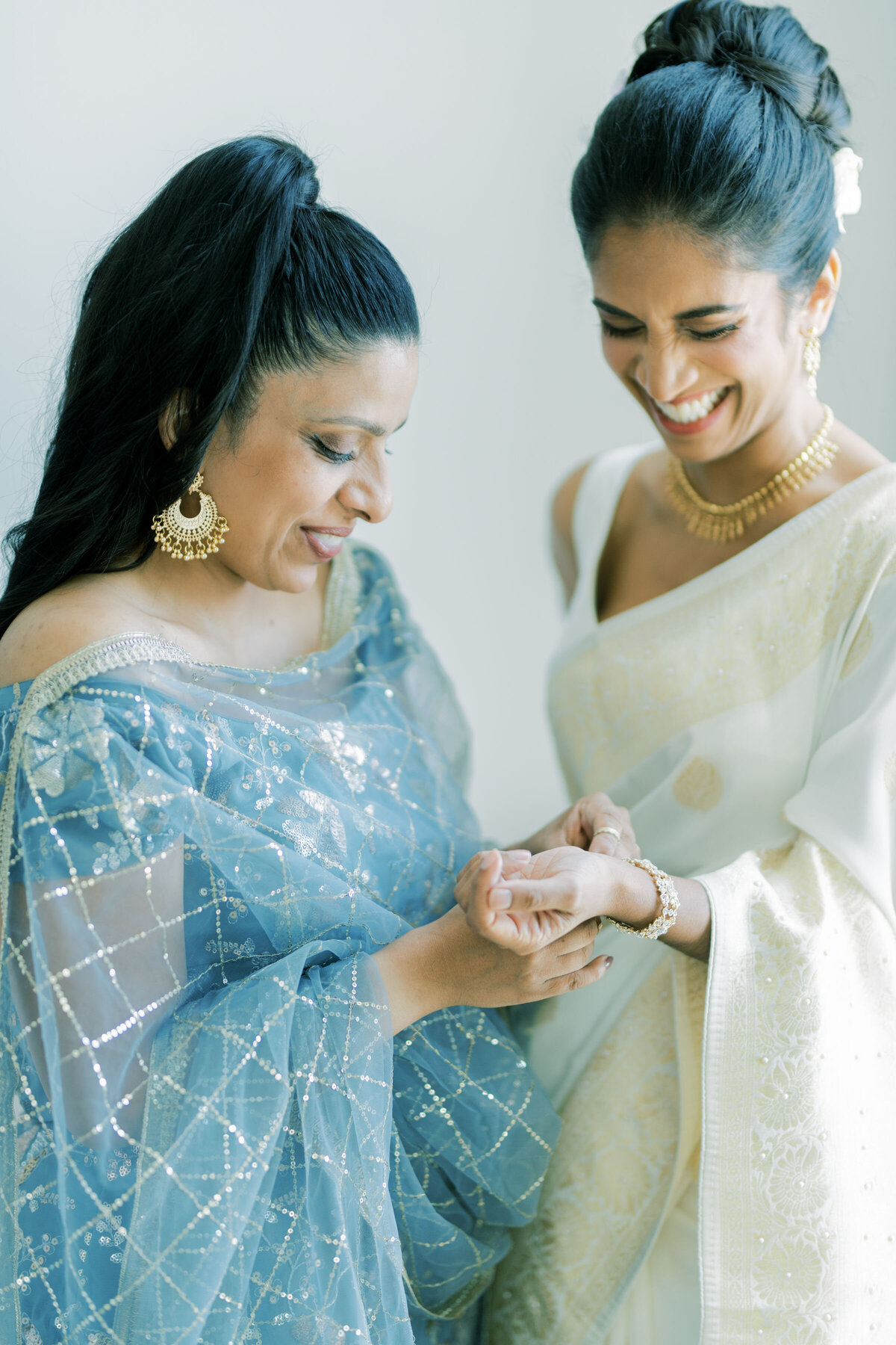 Bridesmaid helps bride with bracelet on wedding day at the pearle hotel