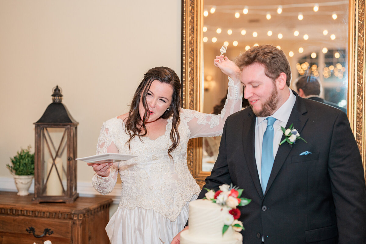 A wedding couple smiling as they cut their wedding cake