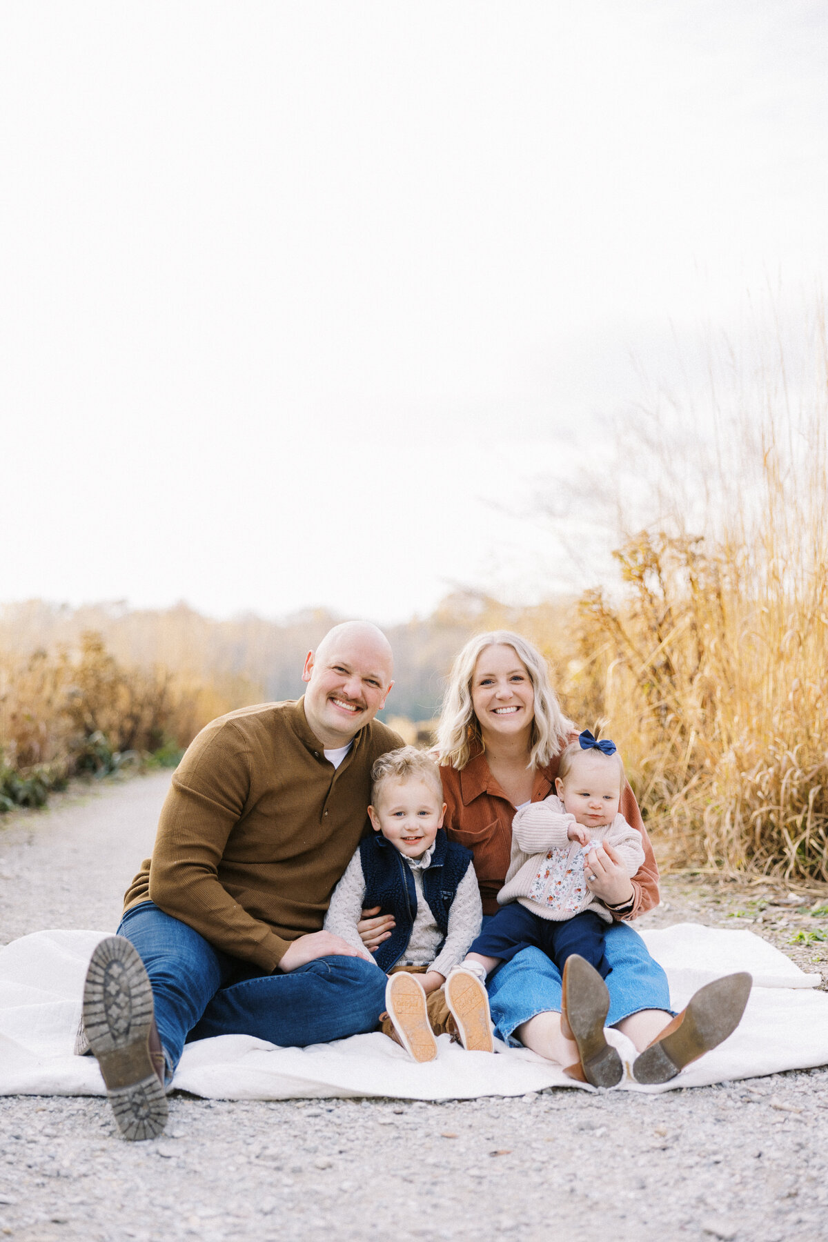 family sitting and smiling at the camera during family photos in indianapoliss