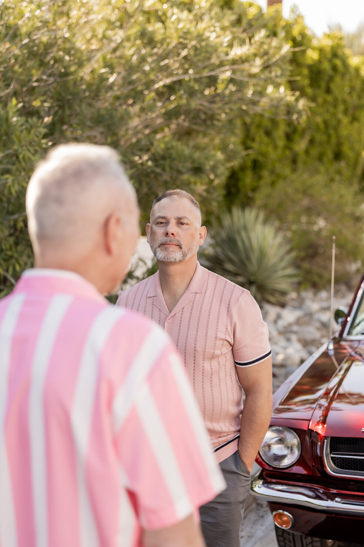 LGBTQ+ couple smiling together in matching pinks, framed by golden light and desert palms in Palm Springs.