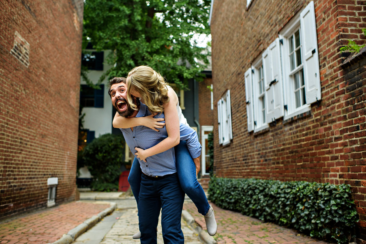 A woman jumps on the back of her fiance during philly engagement session.