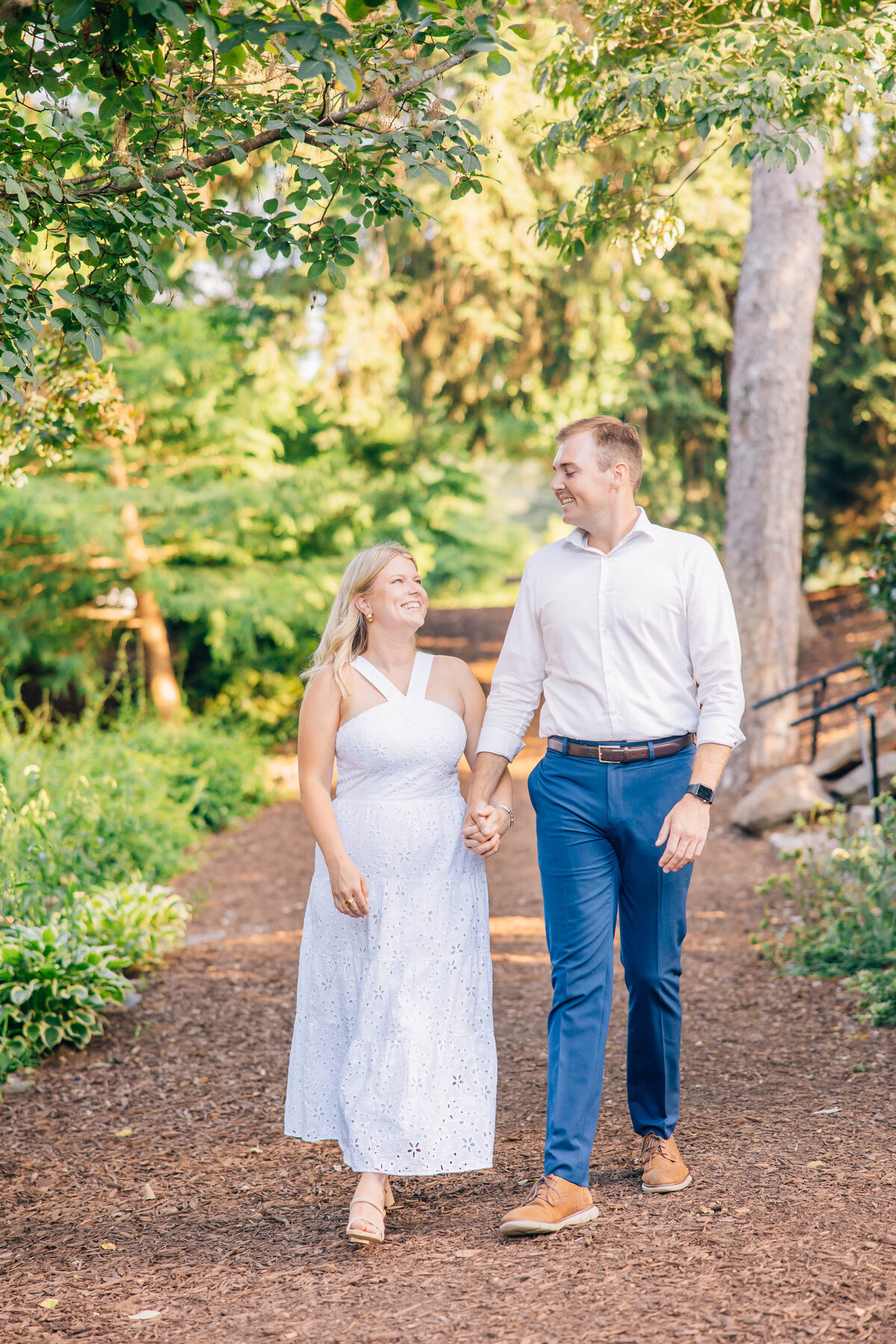 couple walking on path holding hands at the rock quarry in greenville, south carolina