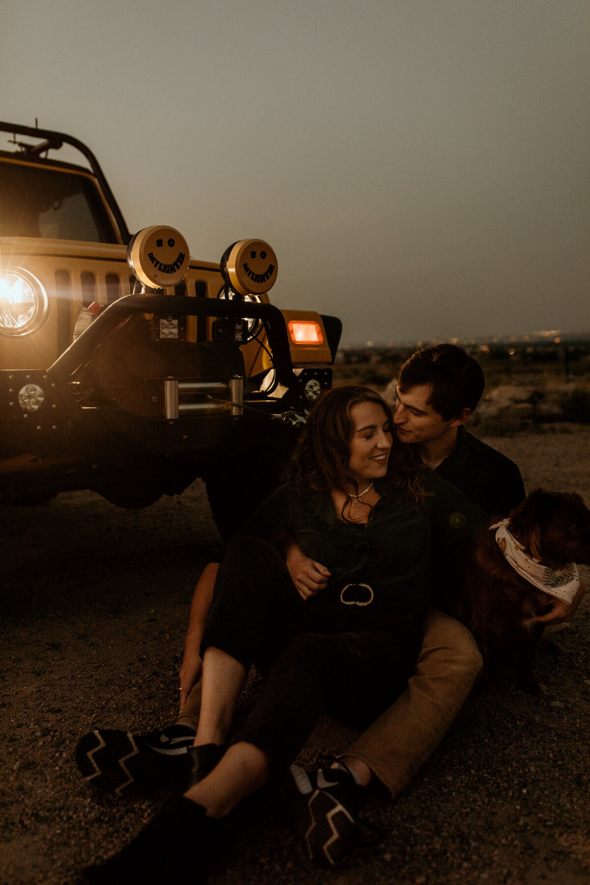 engaged couple sitting in front of jeep at sunrise in Albuquerque