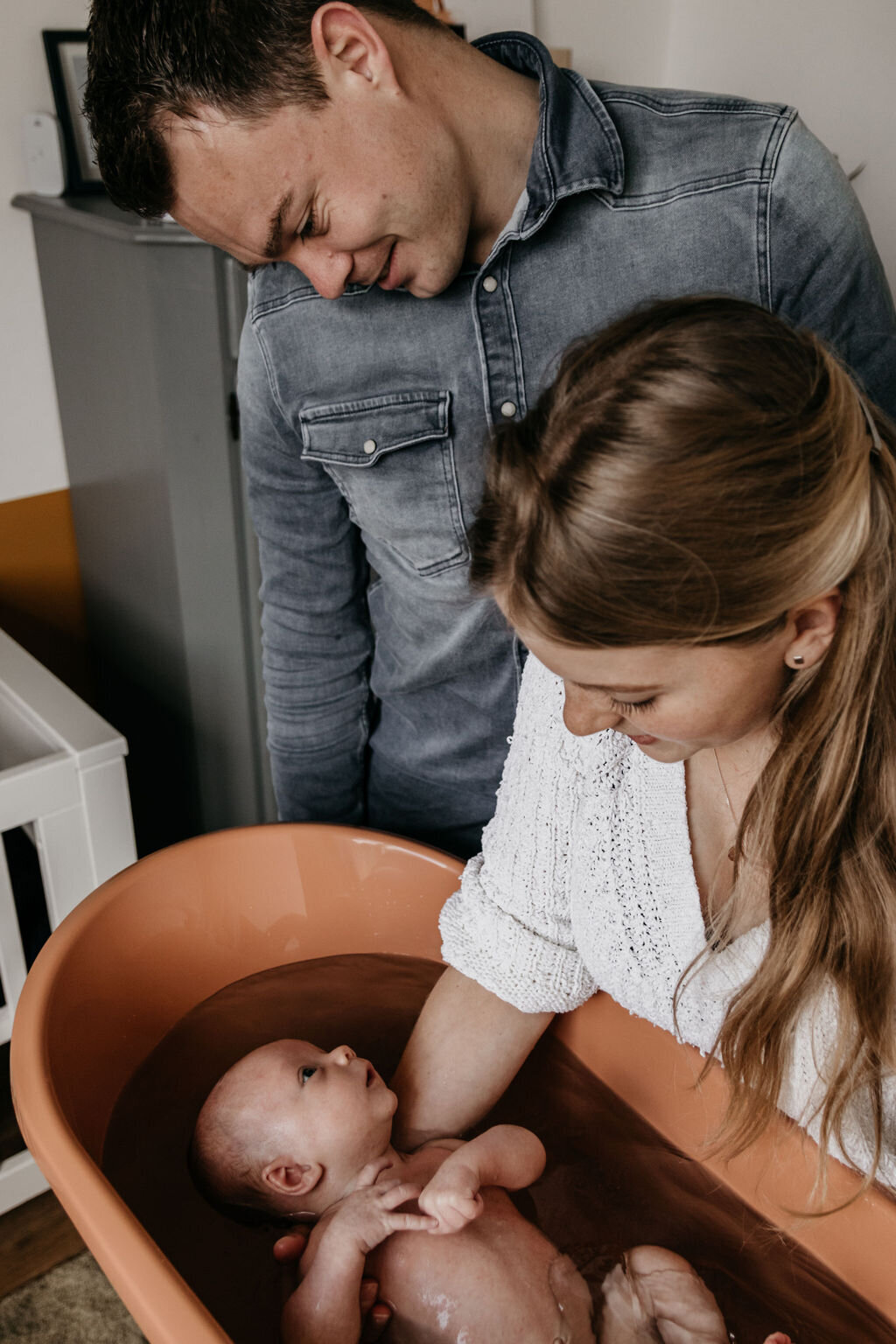 Ouders doen newborn baby in badje tijdens newbornshoot in Noord-Nederland