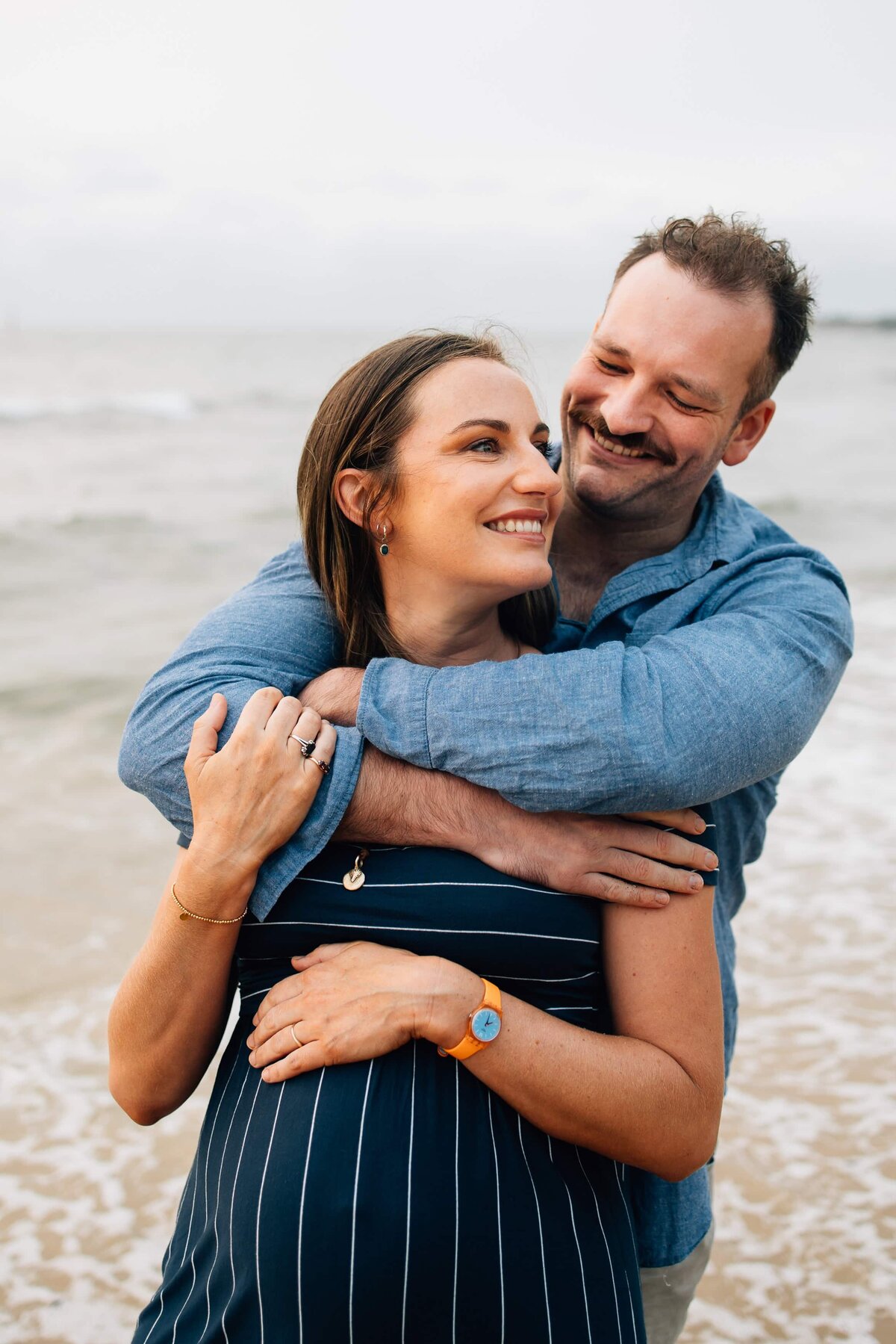 Melbourne beach maternity session image of man hugging pregnant woman.