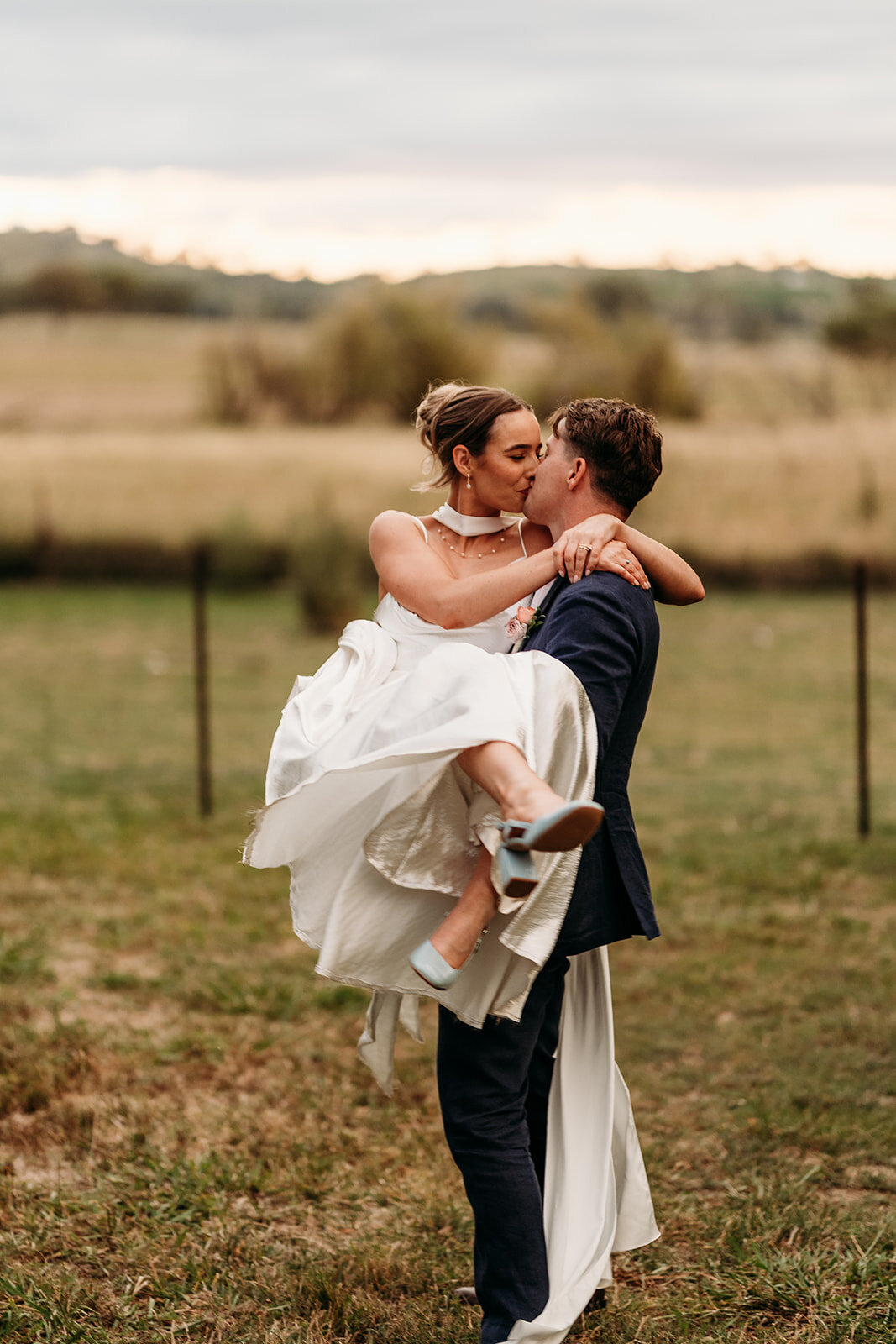 Groom carrying his bride and sharing a kiss during sunset photos at Poachers Pantry