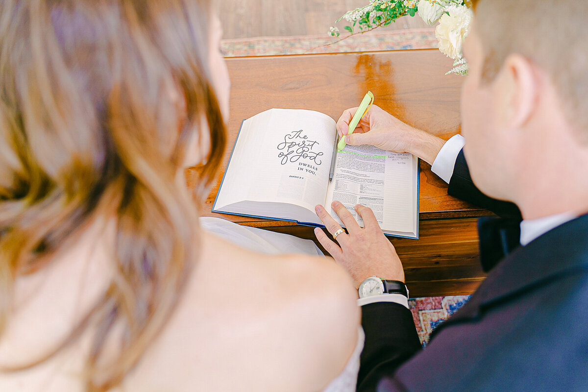 bride and groom highlighting their favorite bible verse in a bible as their guest book