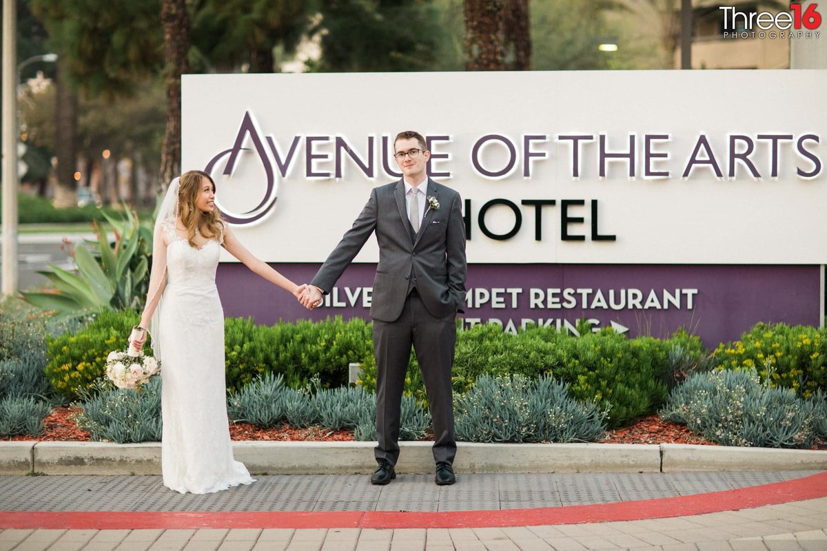 Newly married couple pose for photo in front of wedding venue sign