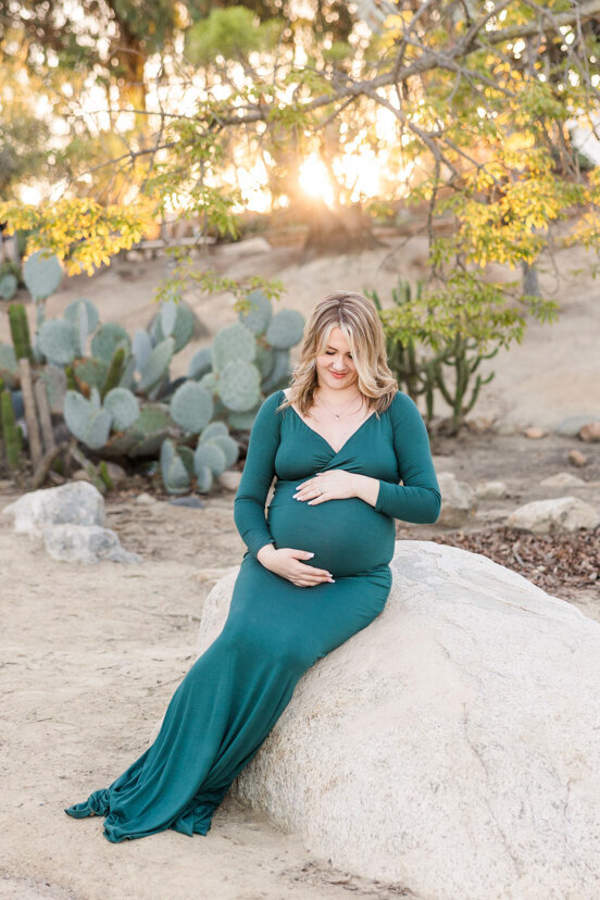pregnant woman sitting on rock in cactus garden