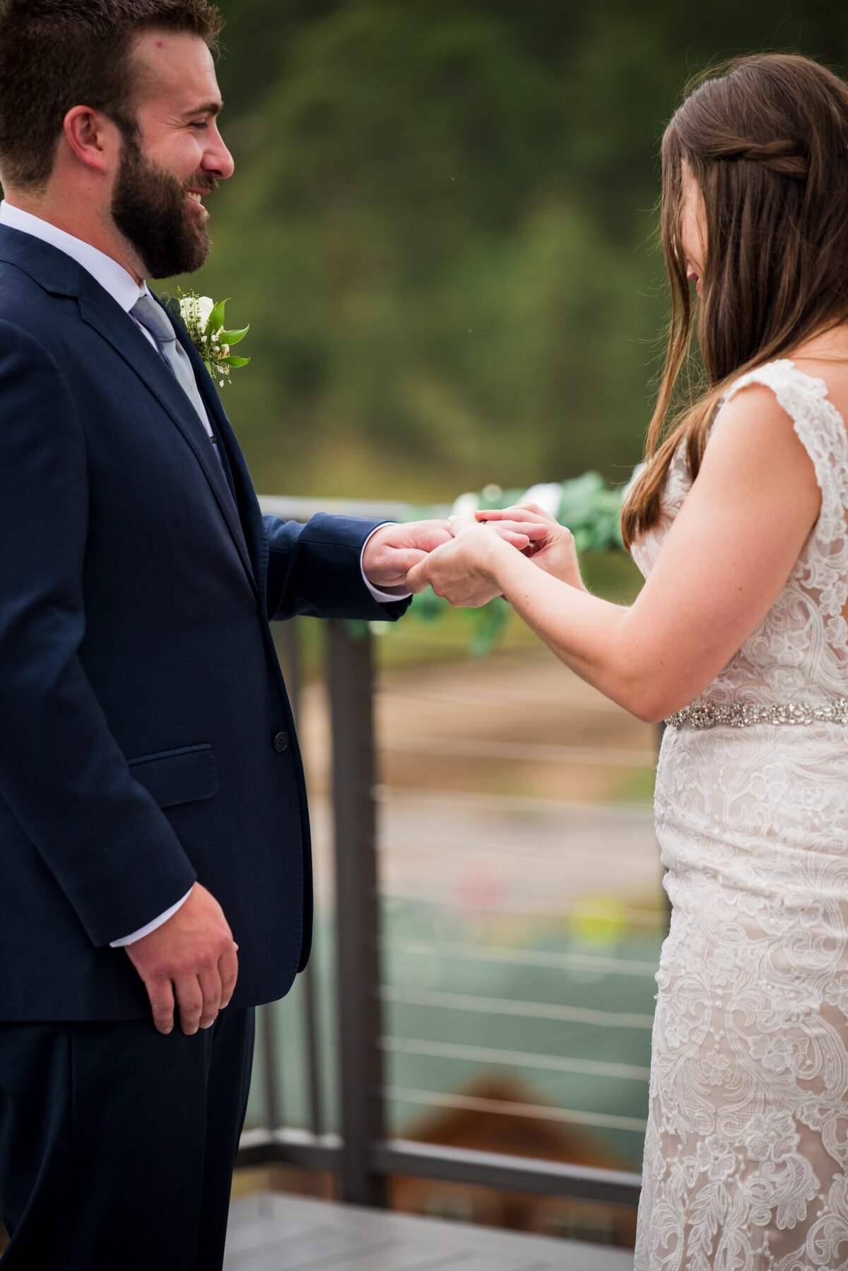 A close up shot of a bride placing the wedding band on her groom's finger.