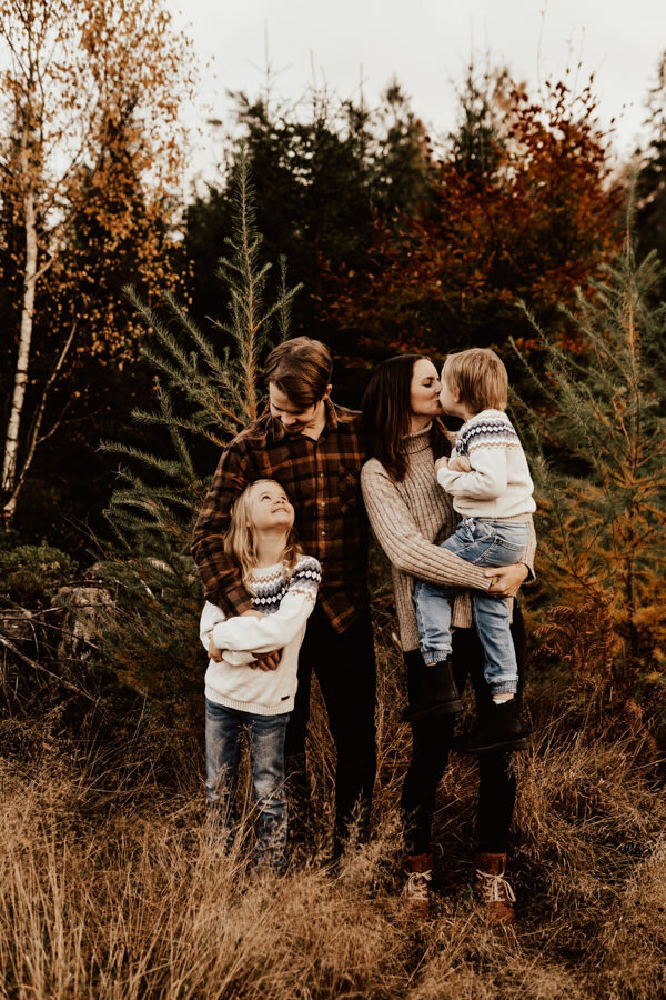 familj står tillsammans i skogen under fotografering