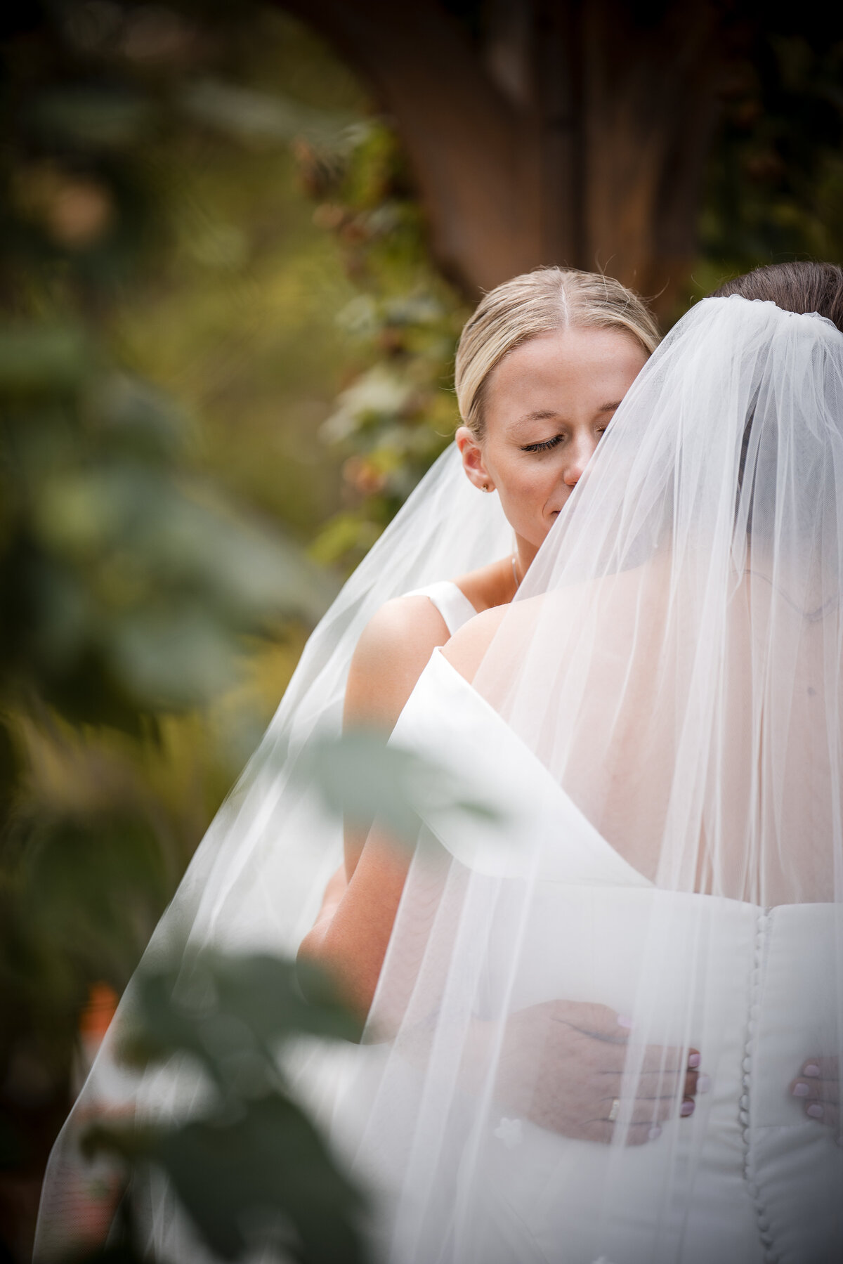 Two brides embrace at a  Fairmount Park Horticulture Center wedding