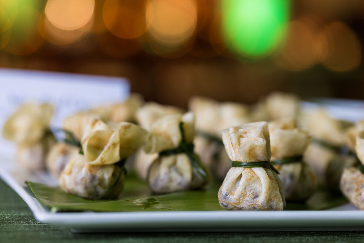 Bite-sized dumplings tied with green chives on a serving tray