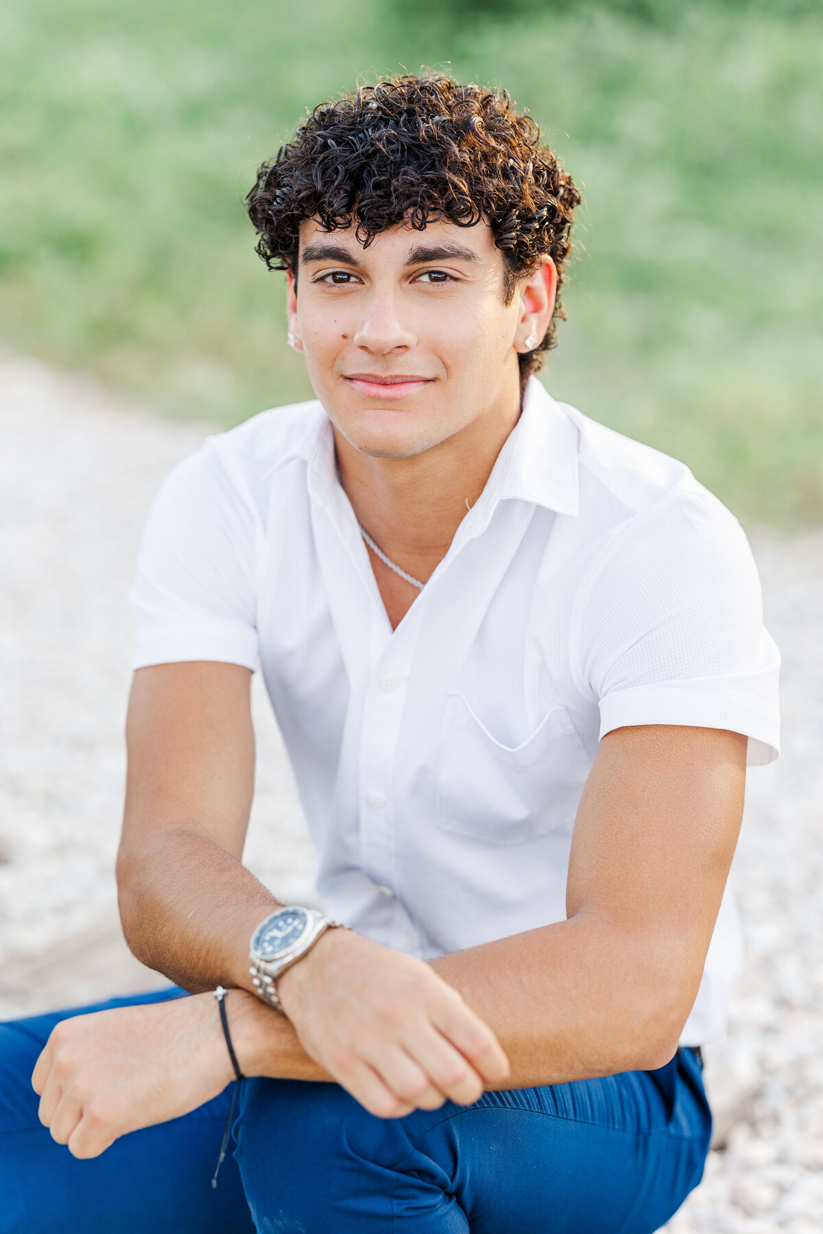 A relaxed senior portrait of a young man in a crisp white shirt, captured with soft golden hour lighting in downtown Fort Worth, Texas. A modern and timeless senior photo by Jennifer Lynn Photography.