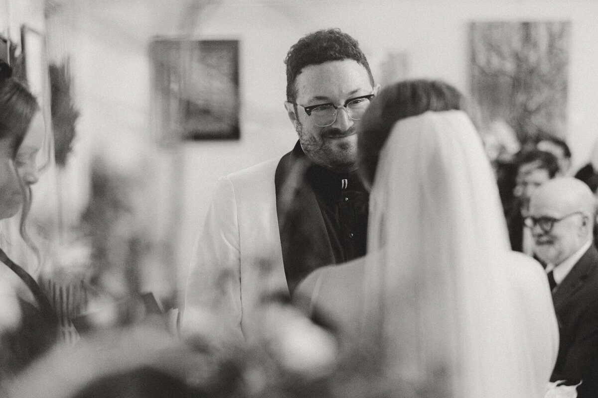 Black and white photo of groom happily looking t the bride