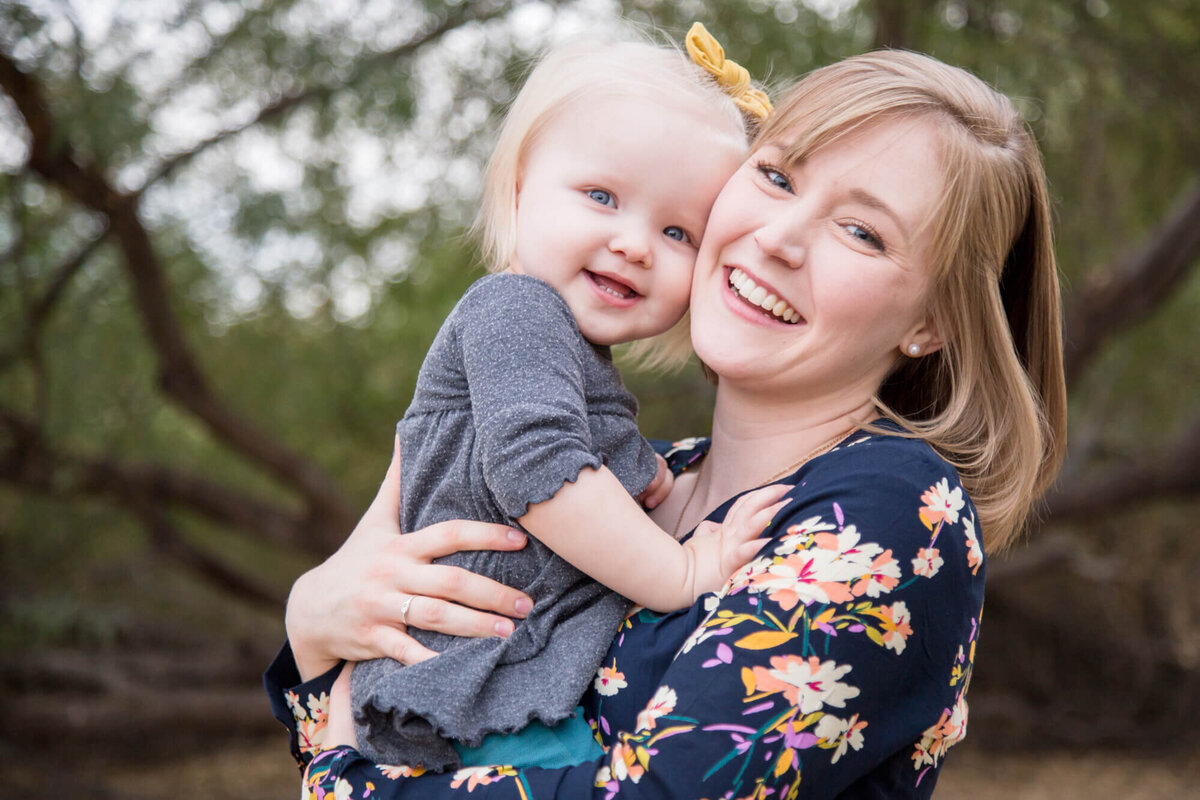 blonde mom in blue flowered dress and toddler girl  hugging and smiling