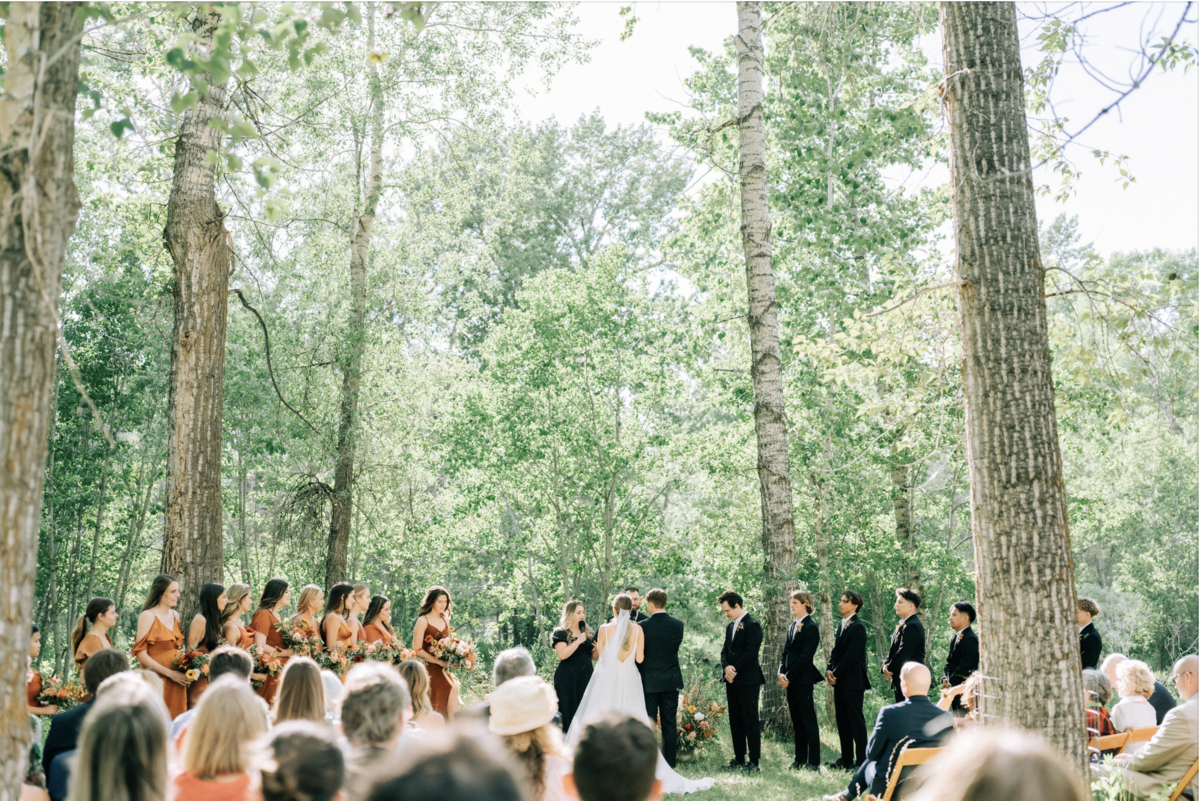 wedding party with bride and groom during their outdoor wedding ceremony in the woods