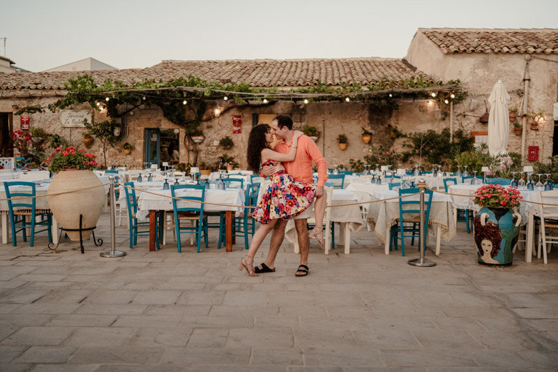 Séance couple romantique en Sicile devant le restaurant Don Peppinu à Marzamemi, capturant un instant complice au cœur d’un décor typique.