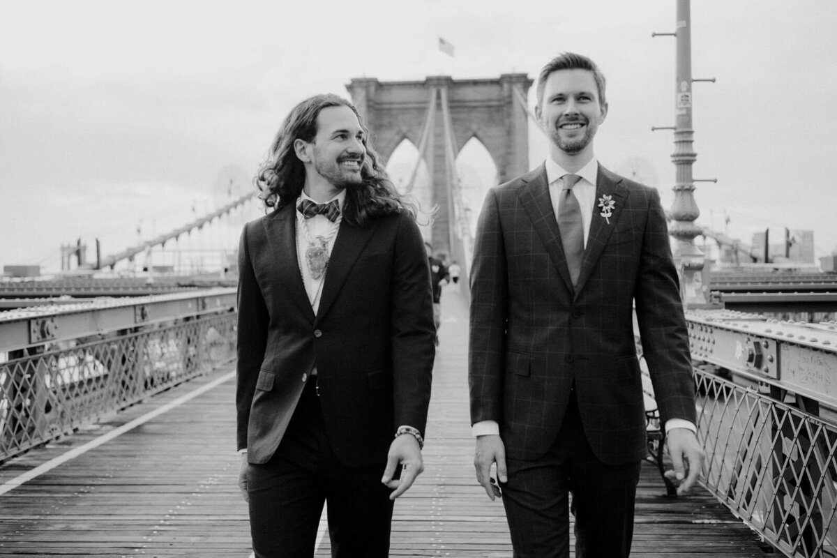 Close-up shot of the two grooms walking on the Brooklyn Bridge. NYC City Hall Elopement Image by Jenny Fu Studio