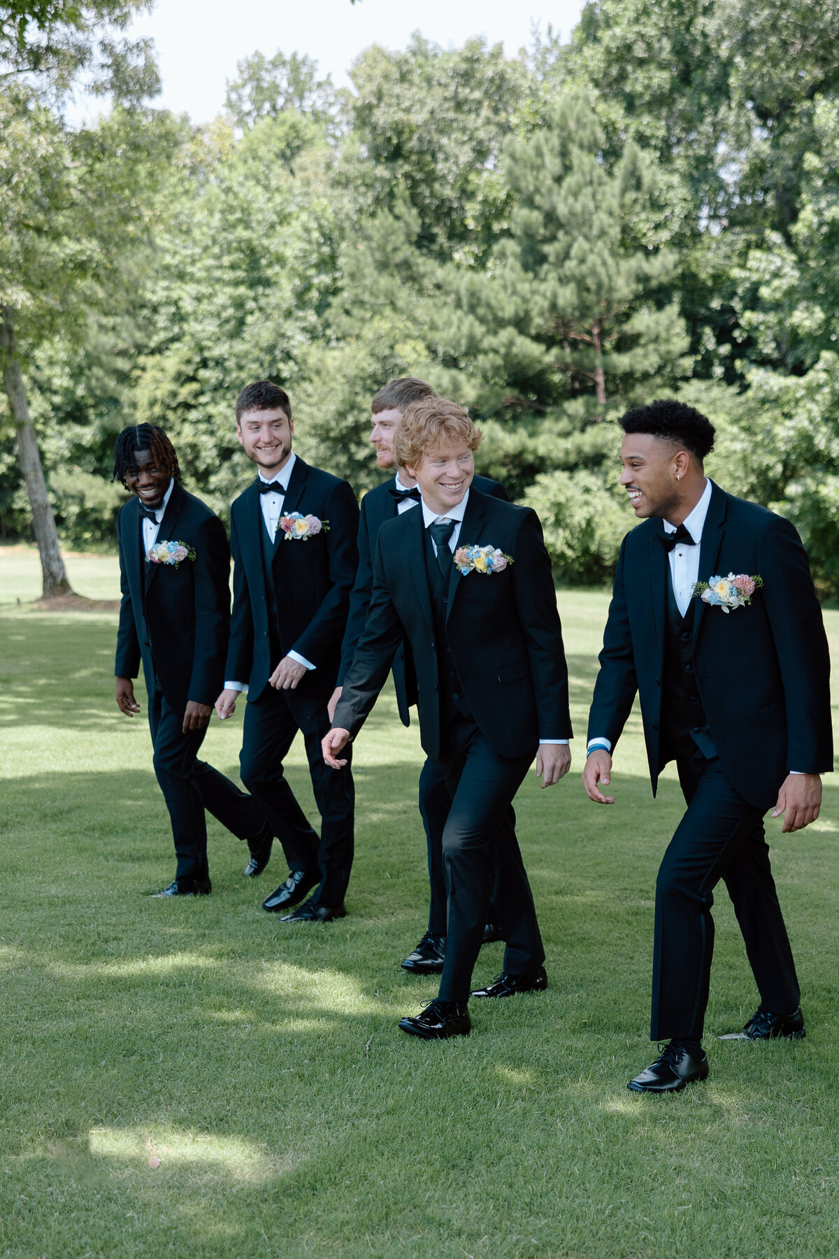 Groom and groomsmen walk as they laugh with one another