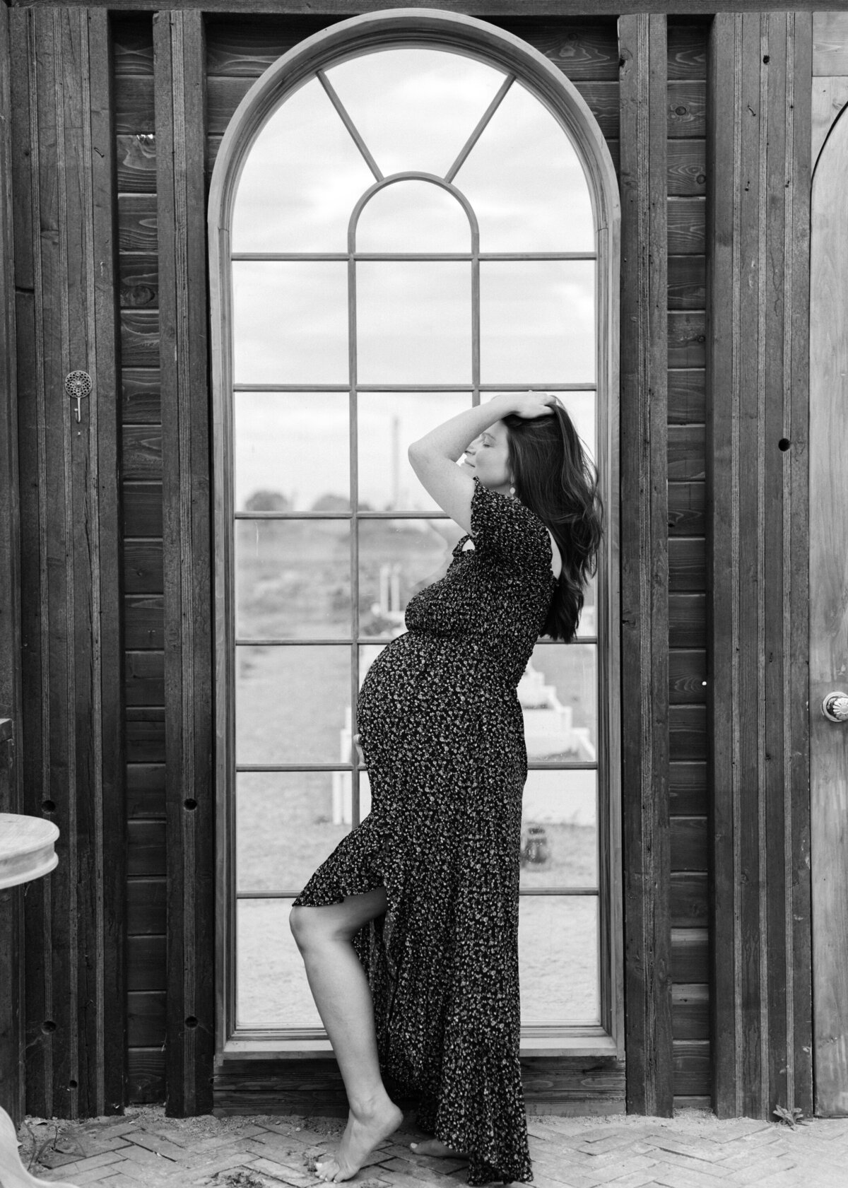 black and white photo of a pregnant woman posing in front of an arched window- photo by Maegan R Photography