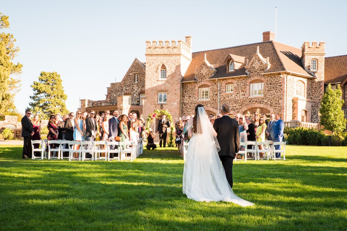 A wide angle shot of a bride and her father getting ready to walk up the aisle at The Highlands Ranch Mansion.