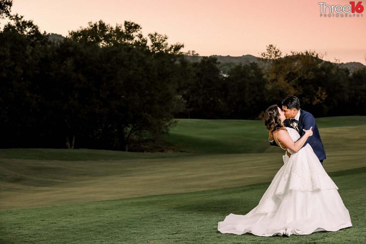 Romantic kiss between Bride and Groom prior to sunset while on the golf course