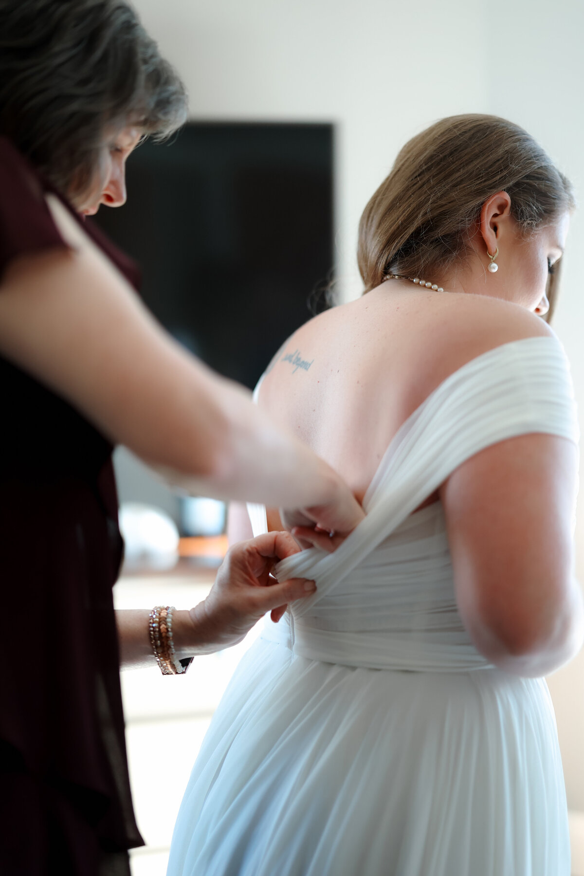 Bride preparing for her wedding day, gently adjusting her veil and dress in a peaceful, light-filled room.