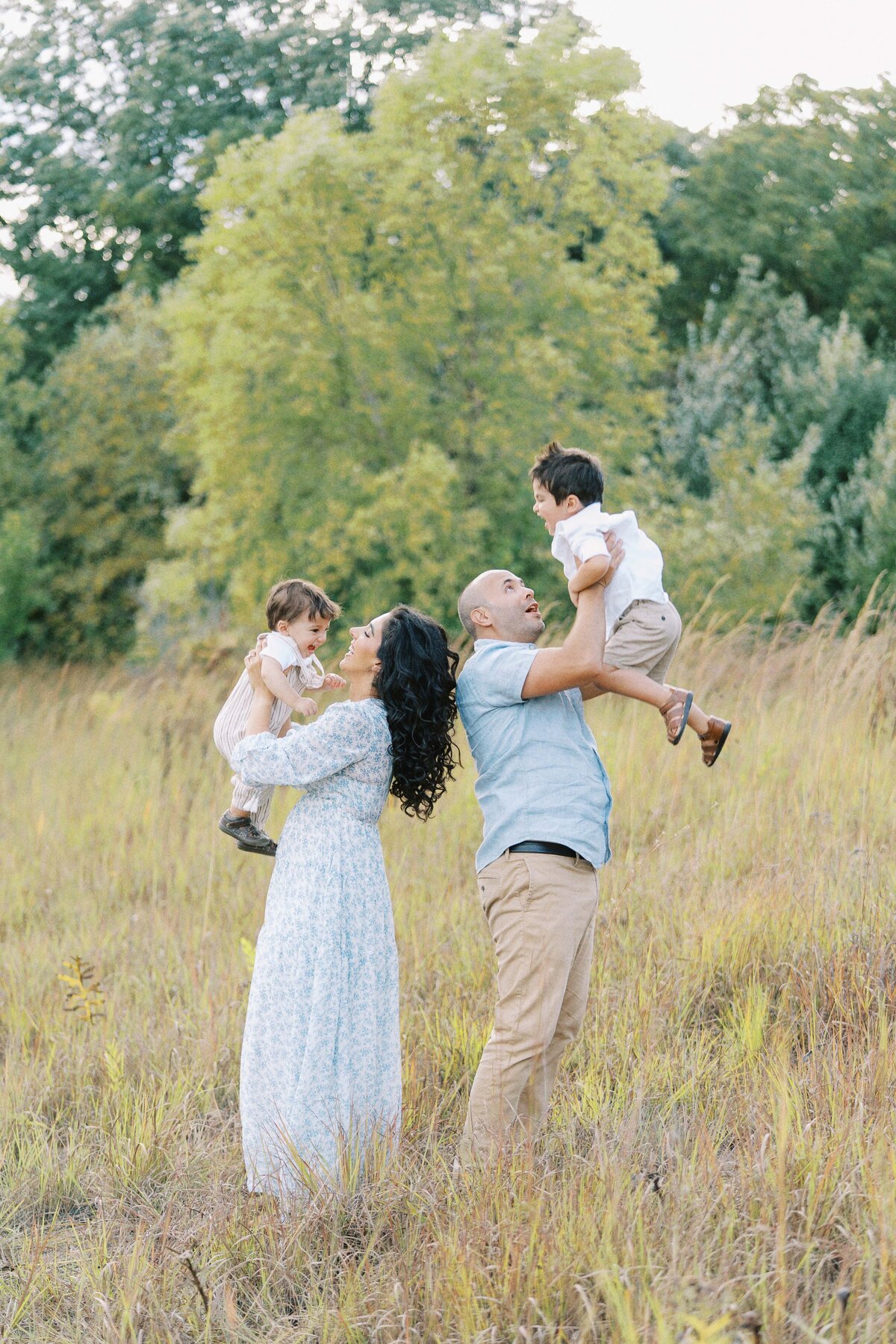 parents tossing their two kids up in the air