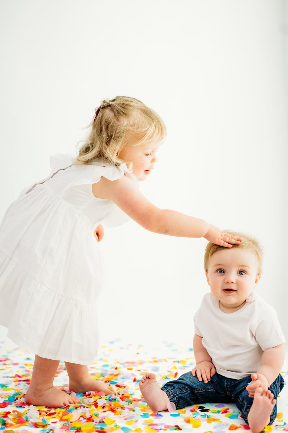 girl puts confetti on baby brothers head