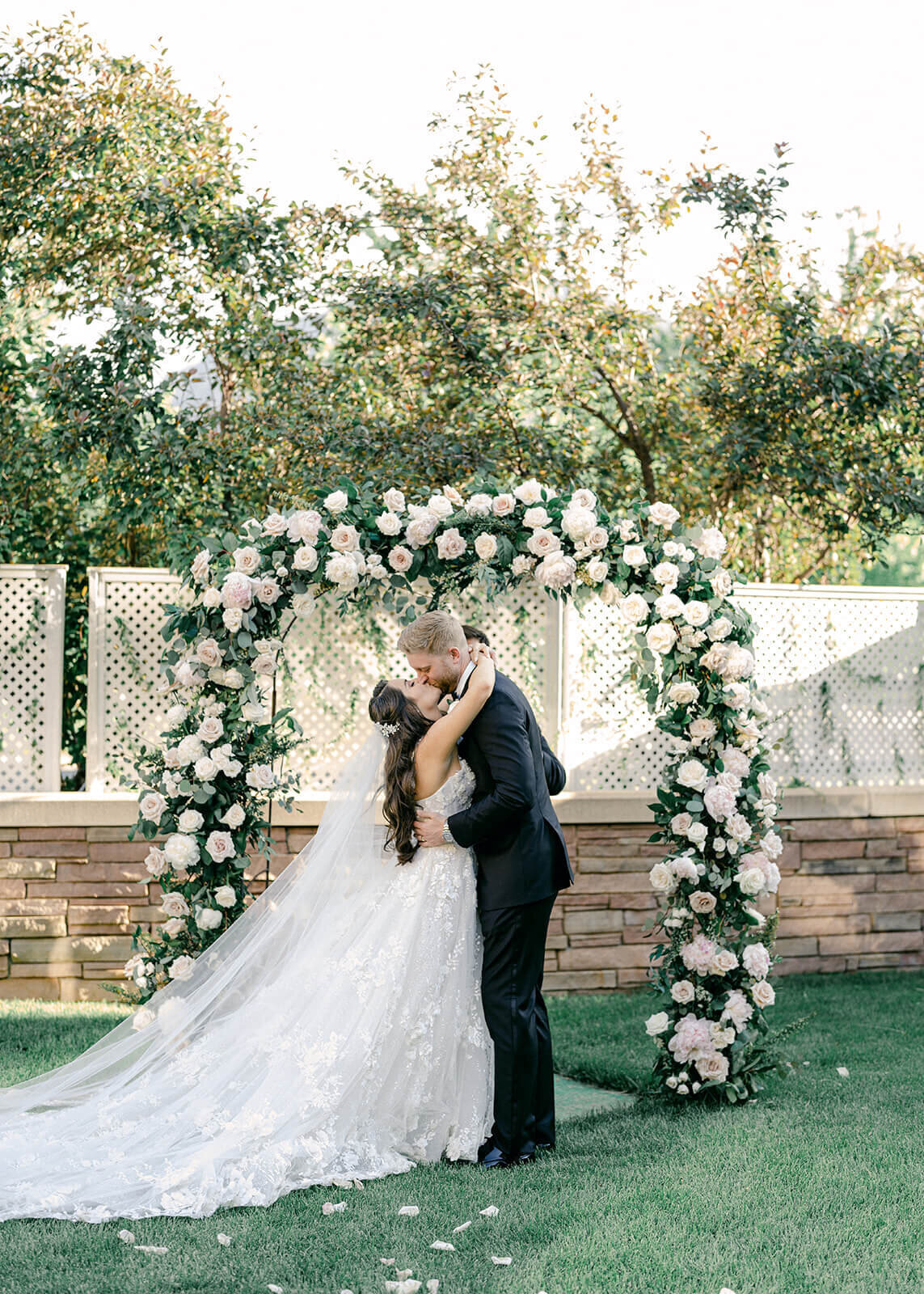 Bride and groom kissing under the custom floral arch at a Boulder Colorado wedding