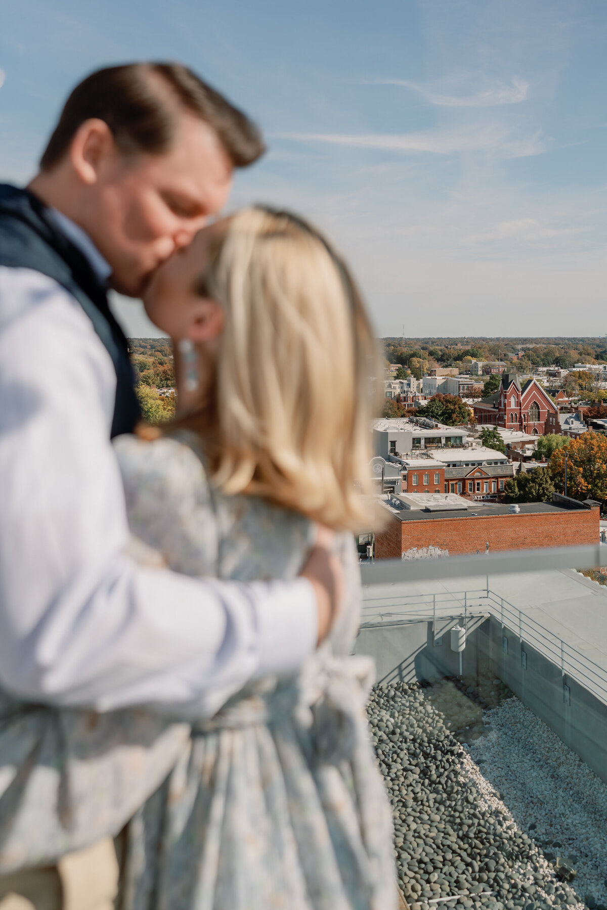 The Quirk Hotel Rooftop Engagement Photos | couple kissing on the rooftop of the Quirk Hotel in downtown Richmond, VA with the city skyline in focus behind them