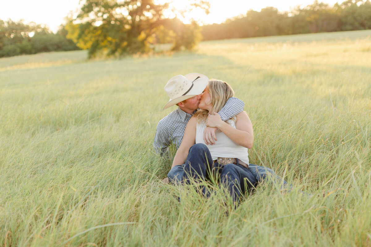 engaged couple sitting in a field
