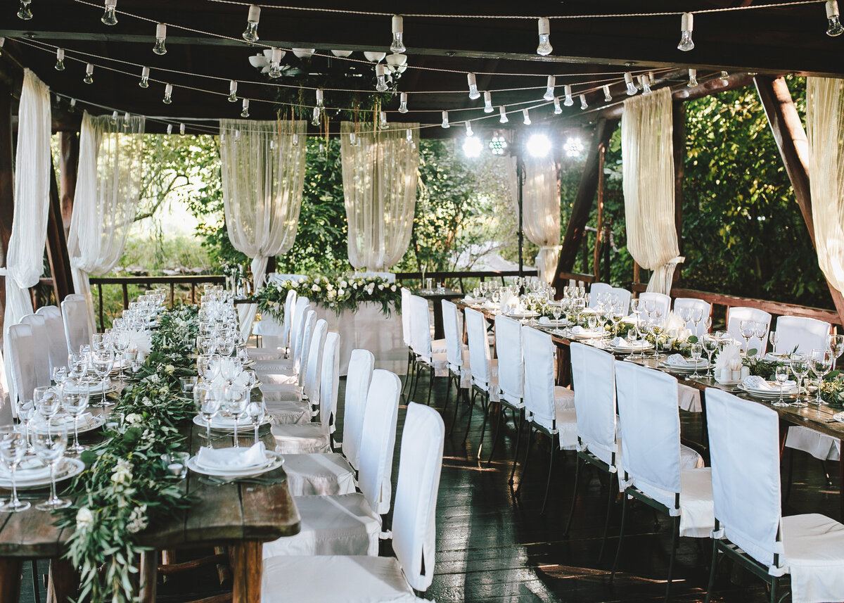 Decorated elegant wooden wedding table for banquet outdoor in garden, with eucalyptus and flowers for a party or wedding.