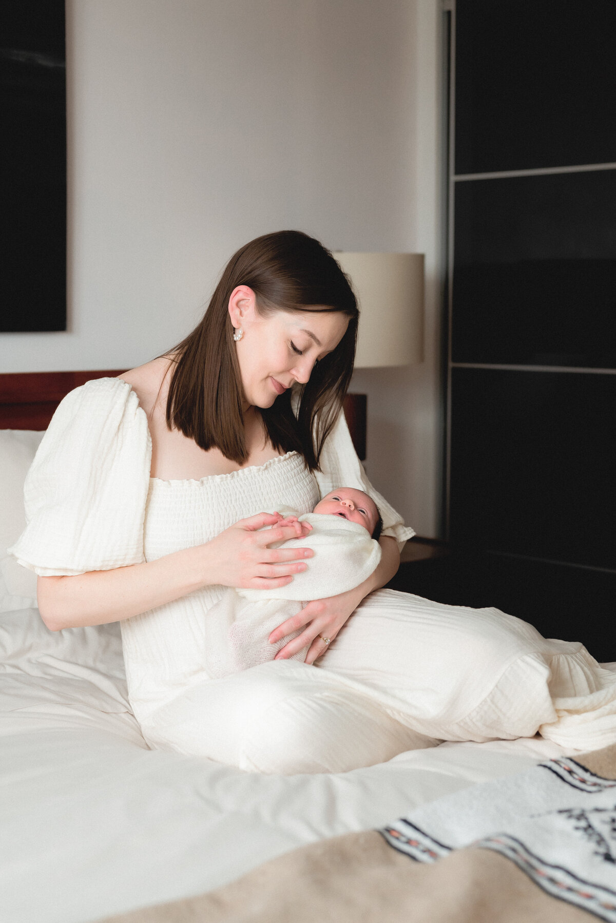 Mother holding newborn baby on bed