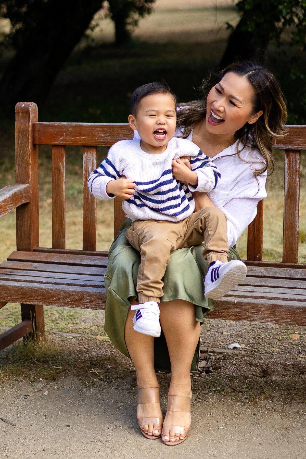 Candid moment of mother and son laughing together on a wooden park bench – Bay Area Family Portfolio - Ellobelle Photography.
