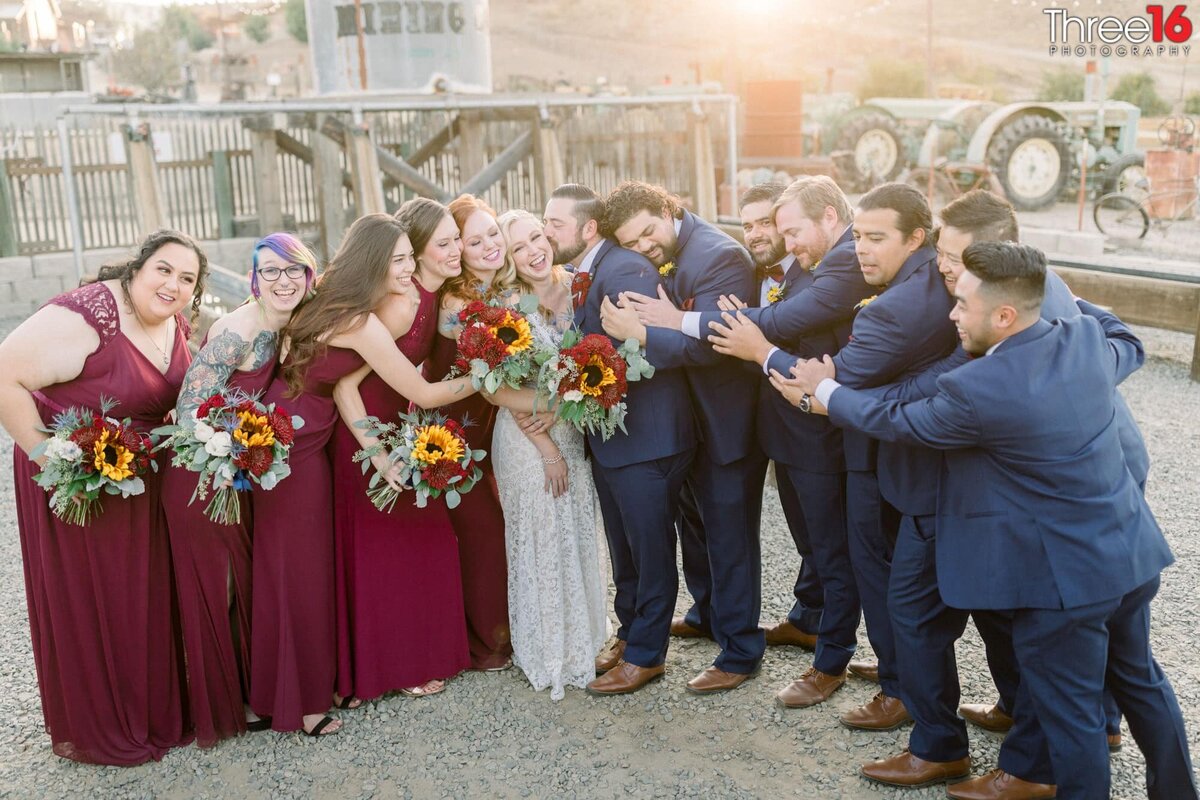 As Groom kisses his Bride's cheek the rest of the wedding party join the lovefest
