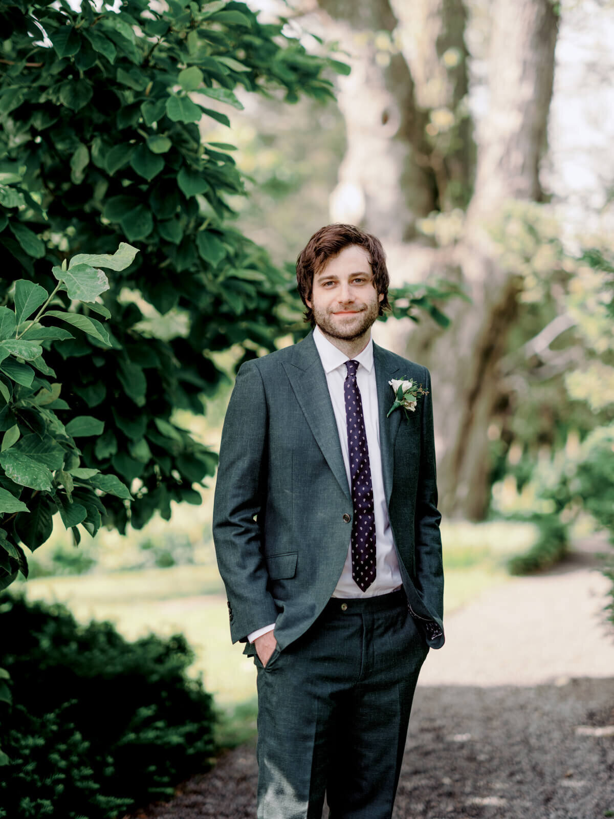 Groom standing with trees on the background