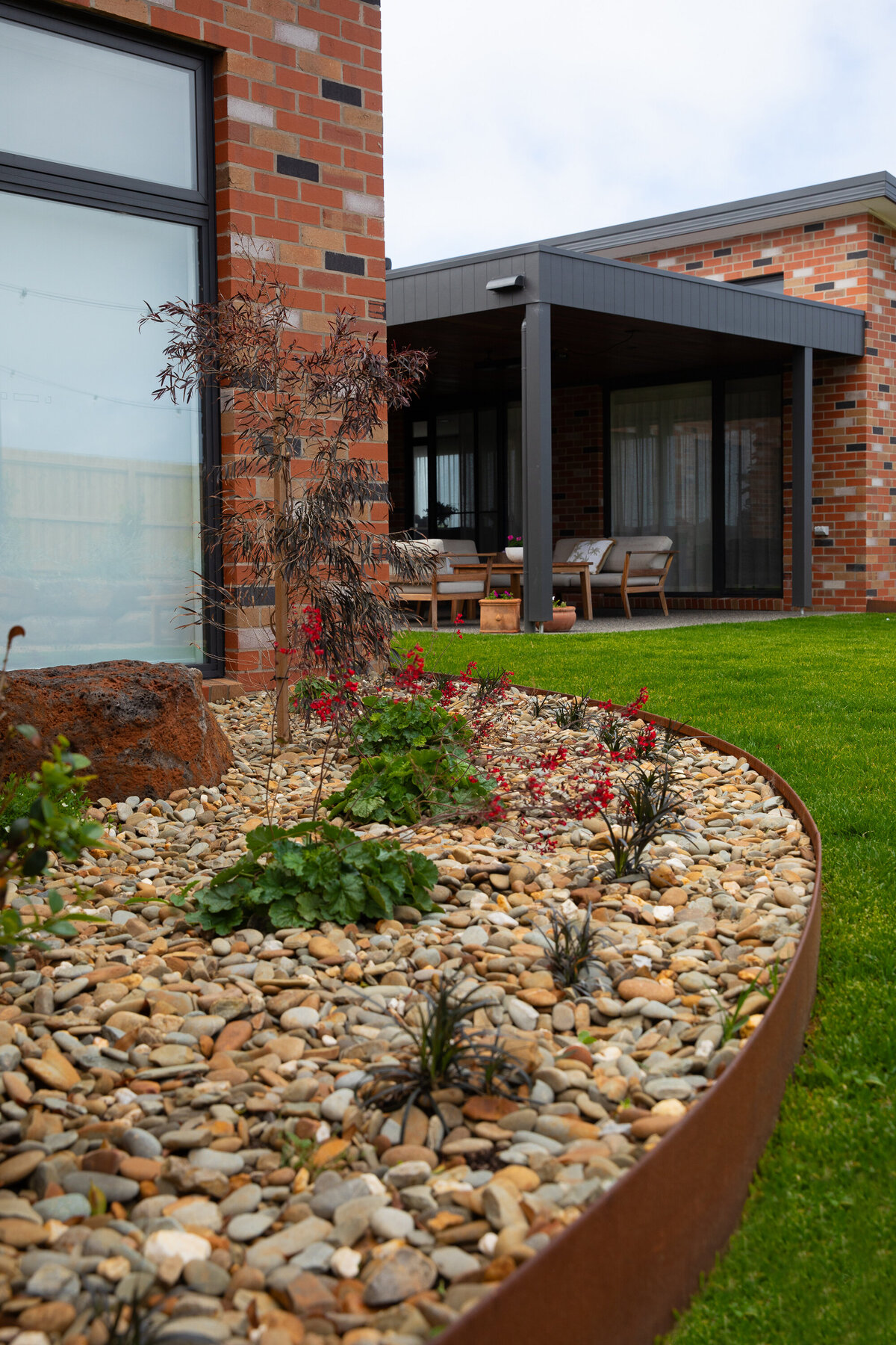 Sleek landscape design with garden bed edging and synthetic grass