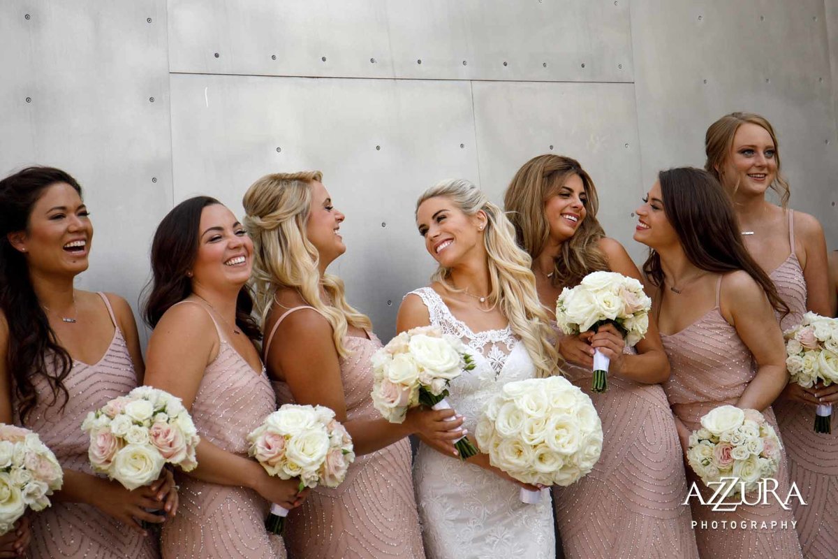 Bridesmaids dressed in blush pink dresses holding bouquets of white roses