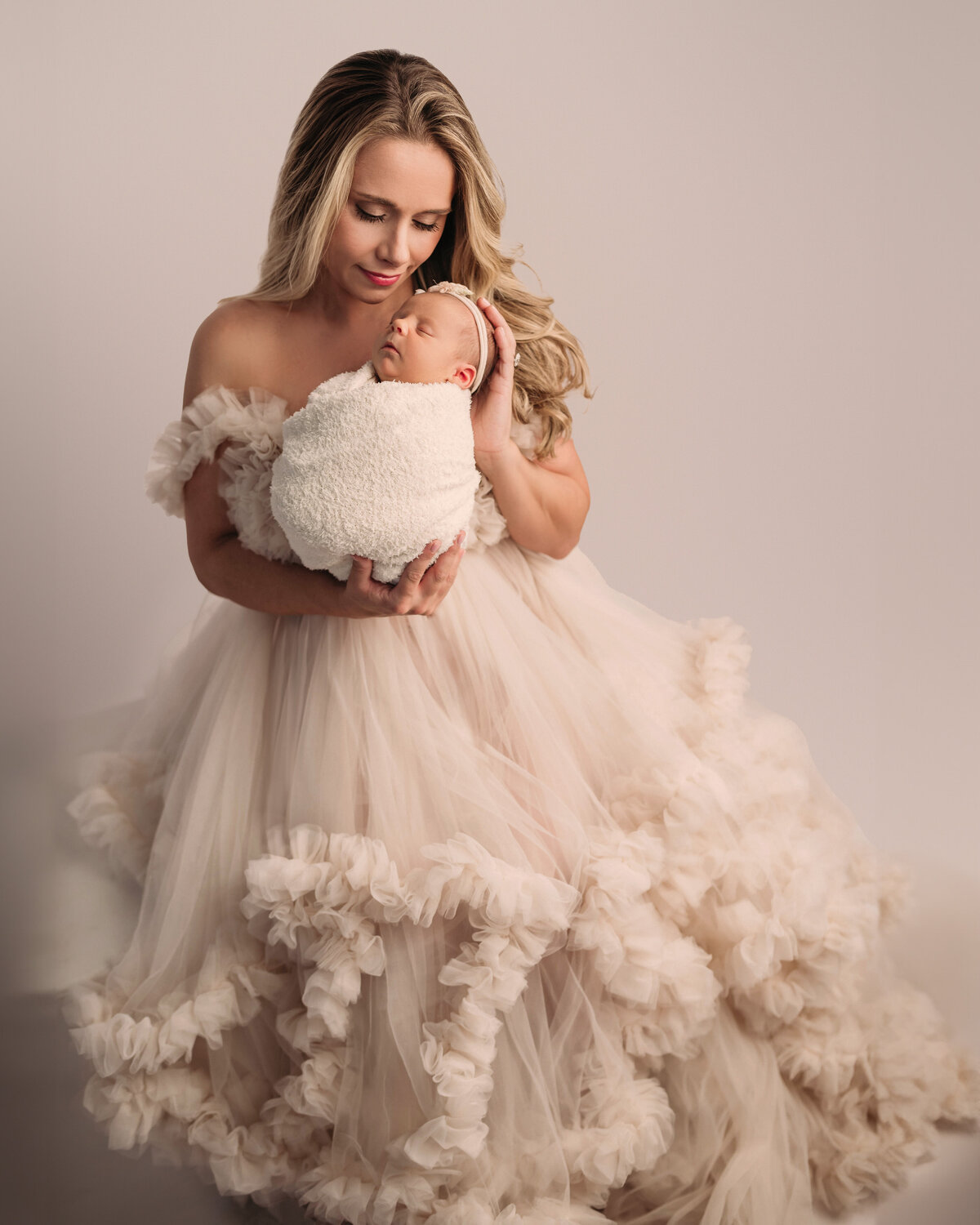 stamford ct newborn photographer captures beautiful new mom wearing gorgeous cream gown holding her swaddles newborn baby girl