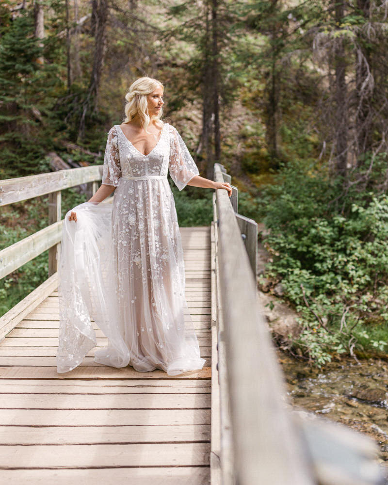 This stunning bridal portrait captures the bride standing elegantly on a wooden bridge in Yoho National Park, near Emerald Lake Lodge. The luxurious setting and natural beauty of the lake and surrounding wilderness create a breathtaking backdrop, adding sophistication to the bride’s special moment.