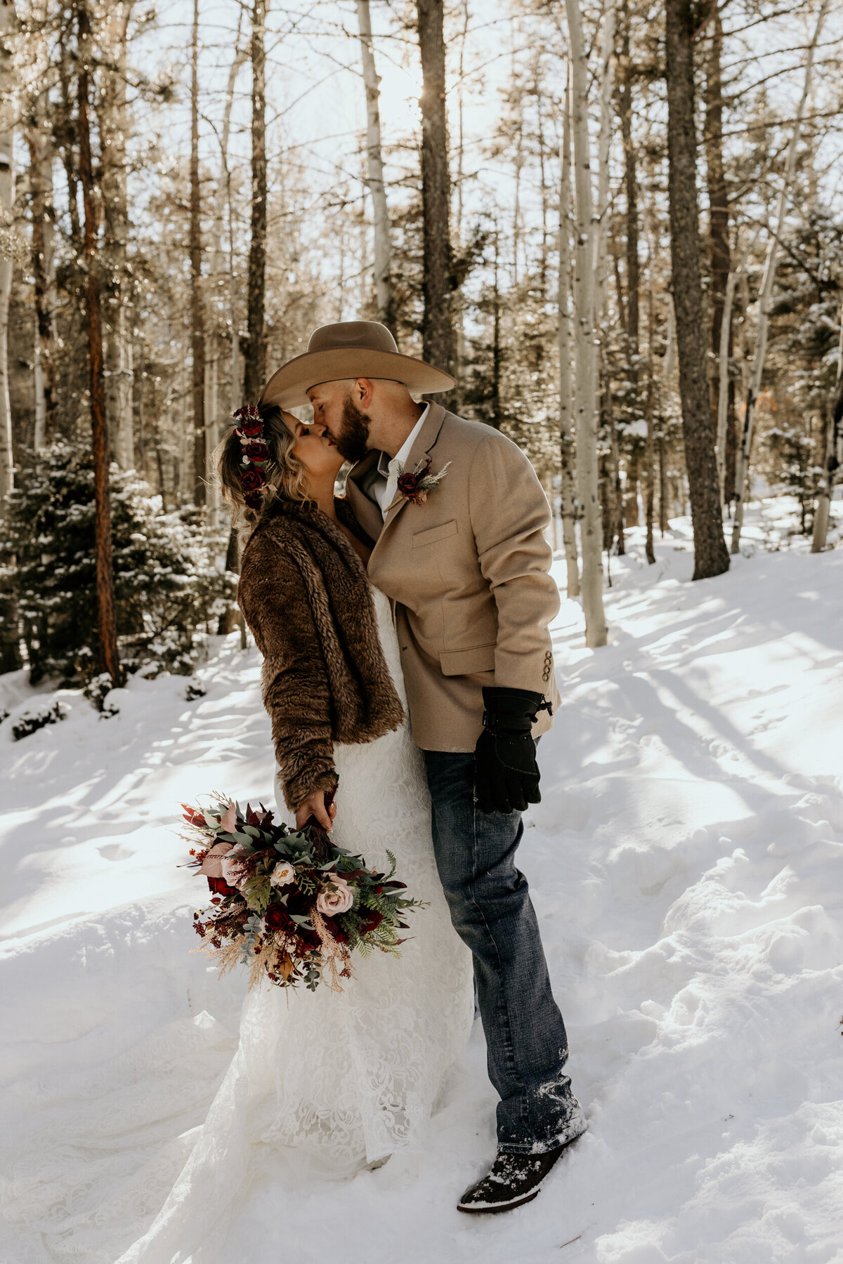 bride and groom kissing in a snowy forest in Angel Fire, NM