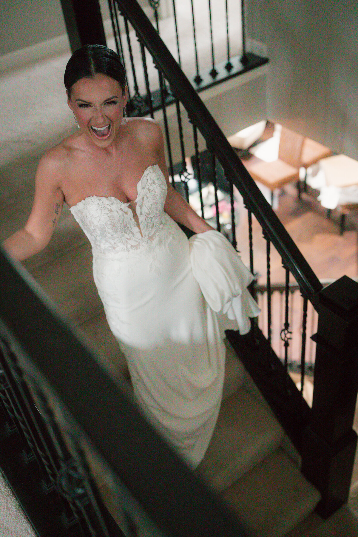 Bride smiling walking down staircase in strapless gown