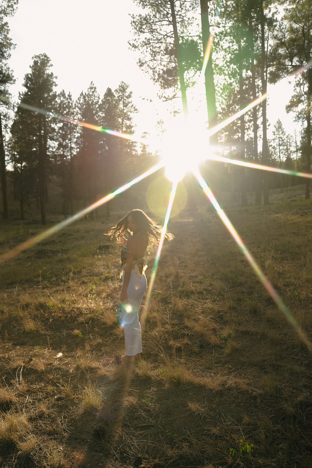 Golden Hour Senior Portrait of Girl Smiling in Forest Wearing White Lace Dress and Denim Jacket