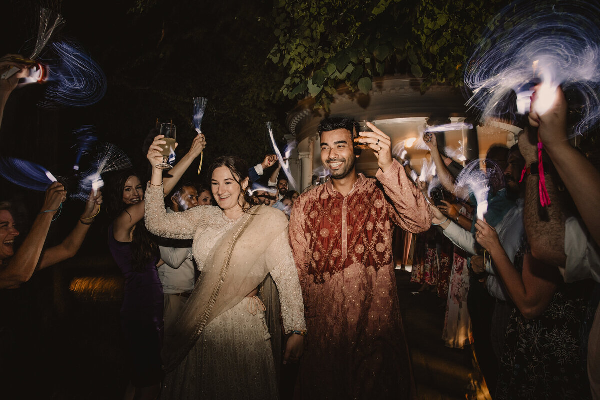A wedding couple and guests holding up glasses in a toast 